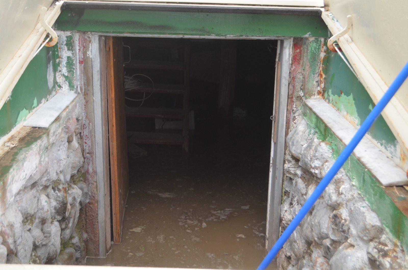 Flooded basement seen through the open cellar door, brown water across the floor