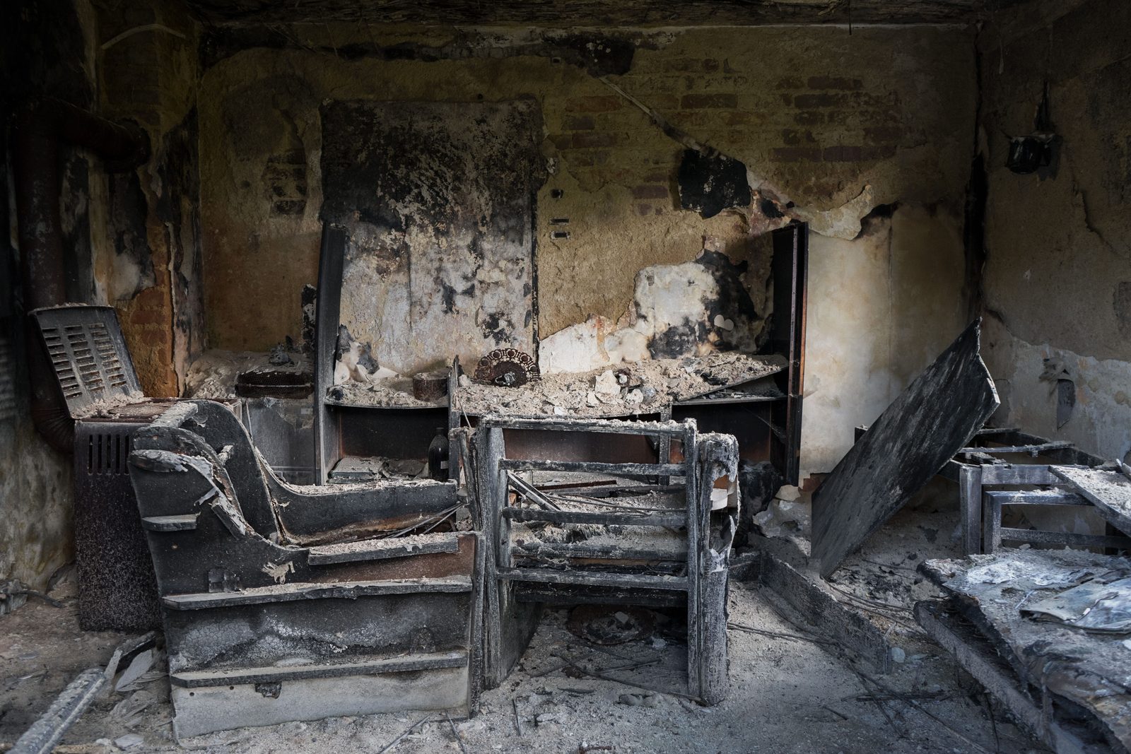Burned living room with charred furniture and soot-blackened walls before cleanup